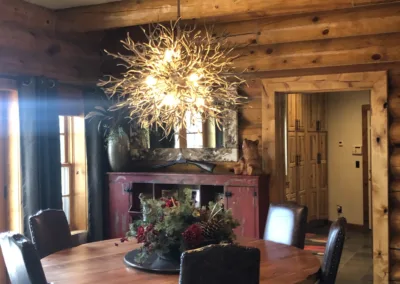 A dining room in a log home with a chandelier.