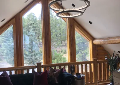 A living room in a log cabin with a chandelier.